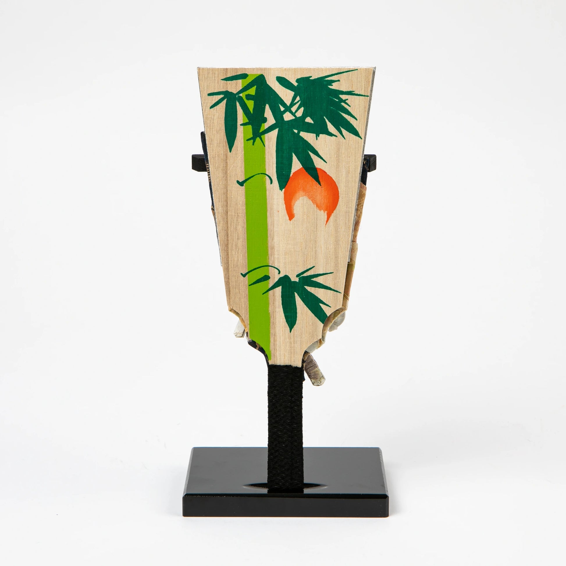 The back of the hagoita paddle, decorated with a painted bamboo motif and an orange sun-like shape.