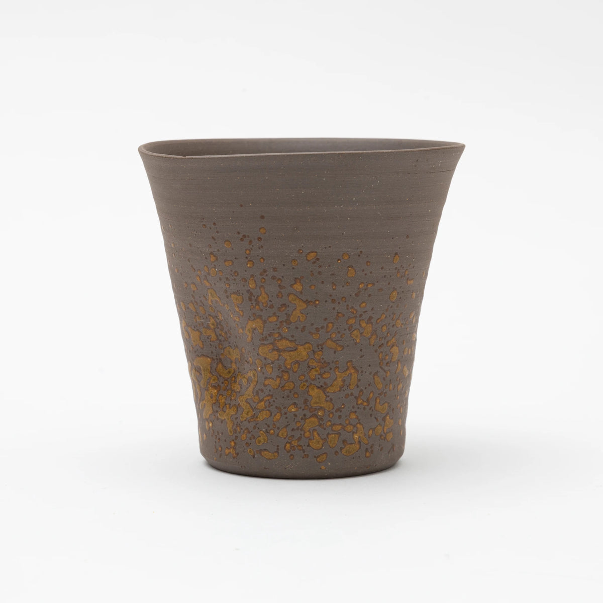A handleless brown ceramic tumbler featuring a heavily textured, speckled ochre glaze on the lower half, set against a white background.