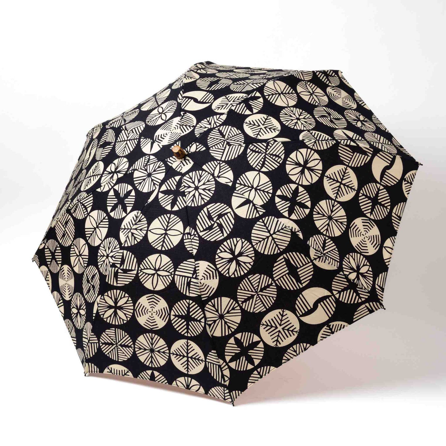 Isa Moyō Folding Umbrella fully opened, showcasing the intricate Pine Tree motif against a dark navy background.