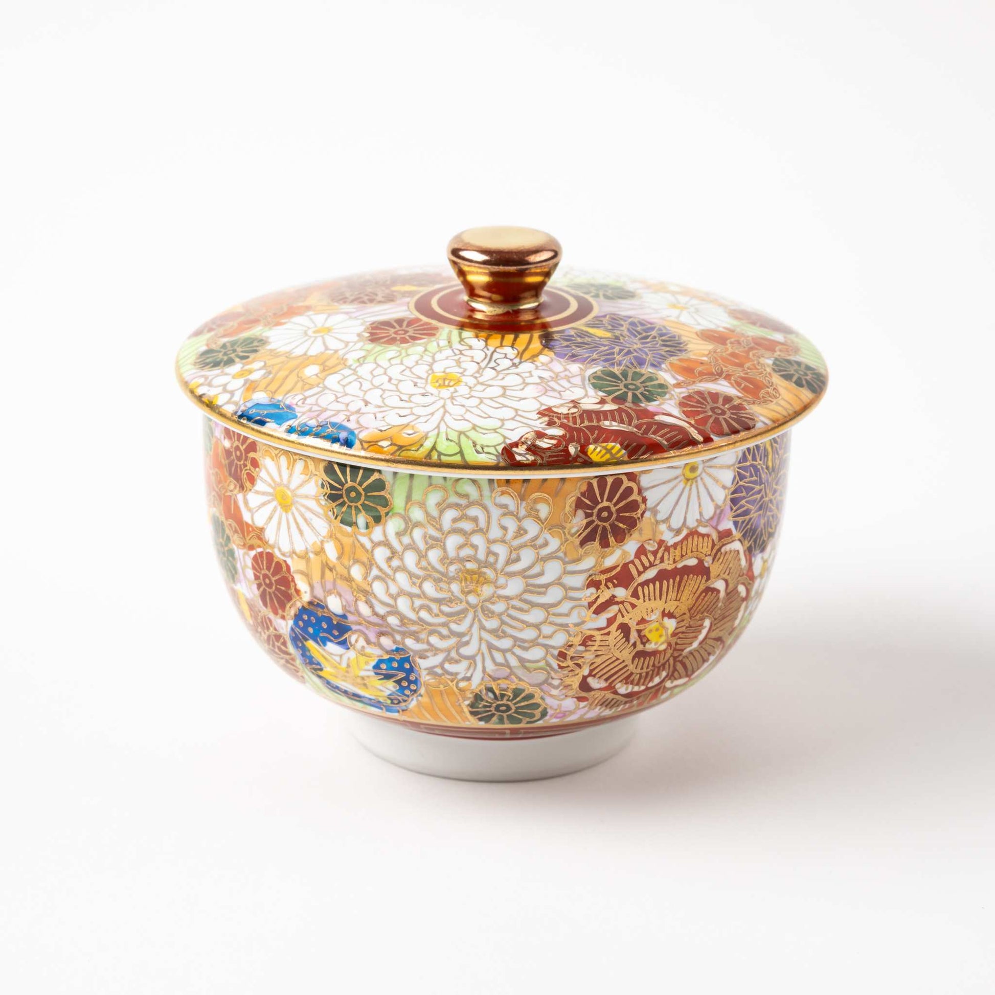 Close-up of a tea cup from the Kutani Blooming Flowers tea set, adorned with vibrant chrysanthemum motifs in red, green, and gold, with a matching lid.