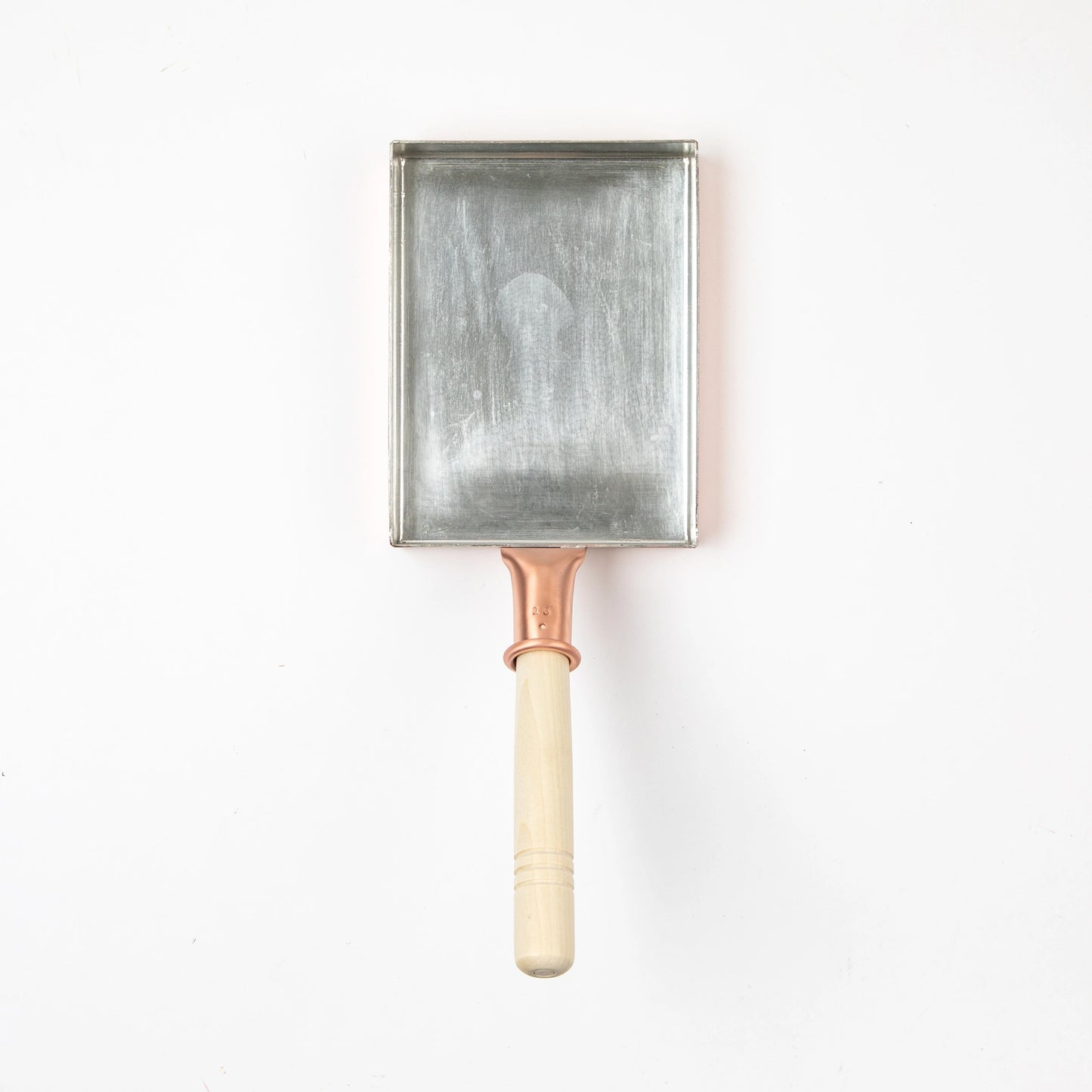 Copper tamagoyaki pan with a light wooden handle, photographed from above on a white background.