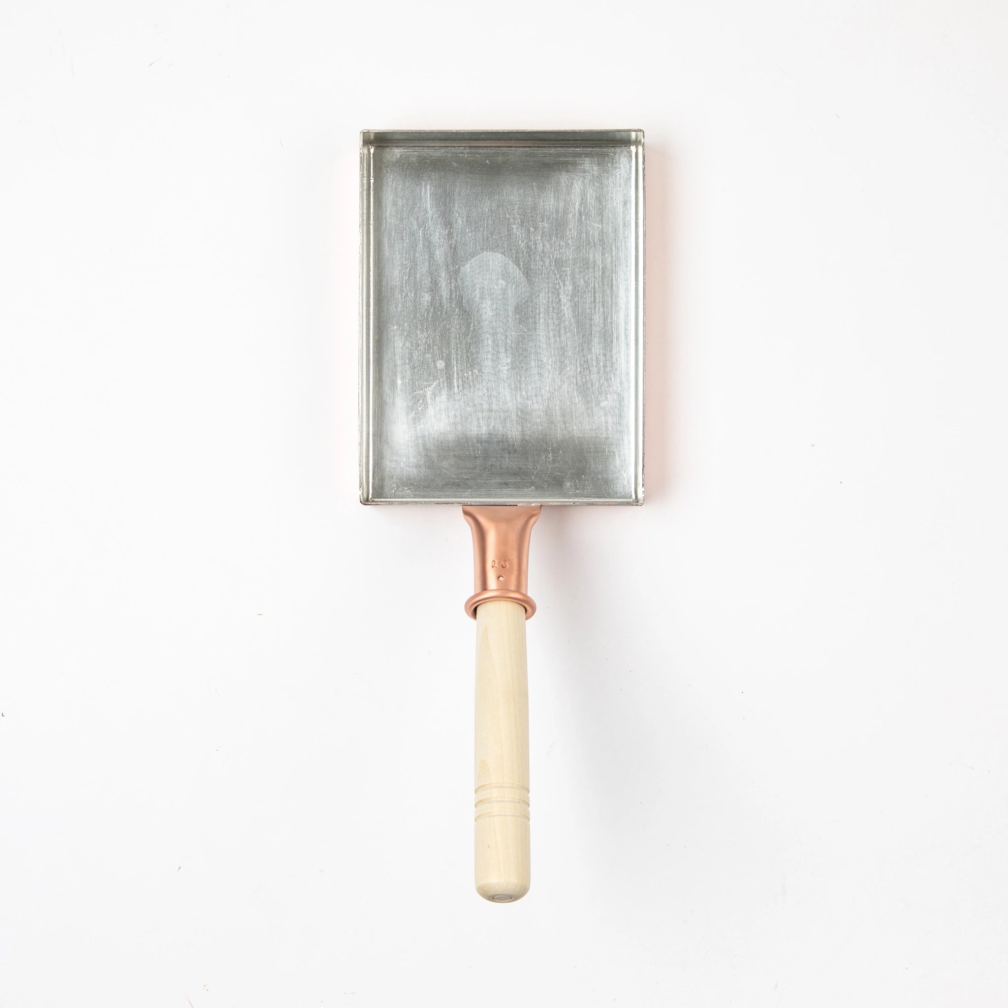Copper tamagoyaki pan with a light wooden handle, photographed from above on a white background.