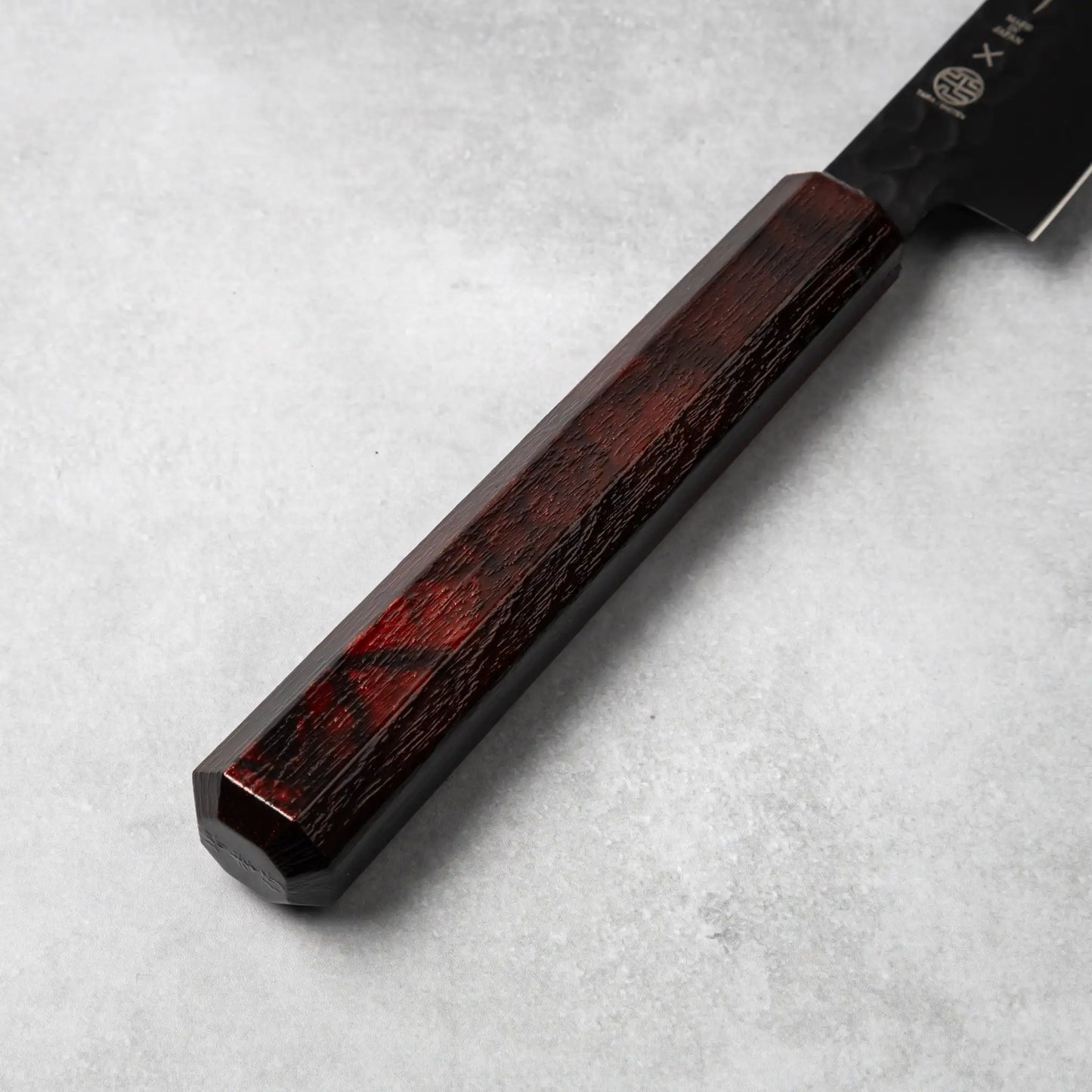 A detailed view of the burgundy resin handle of the Sakai Takayuki Kurokage VG10 petty knife, highlighting its smooth finish and subtle marbled design.