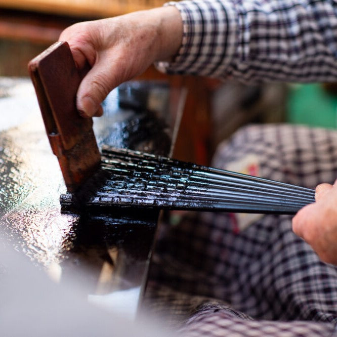 Artisan painting the lacquer on the chopsticks