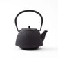 Side view of the black Nanbu cast iron teapot with a dotted pattern, highlighting its curved spout and ergonomic handle.