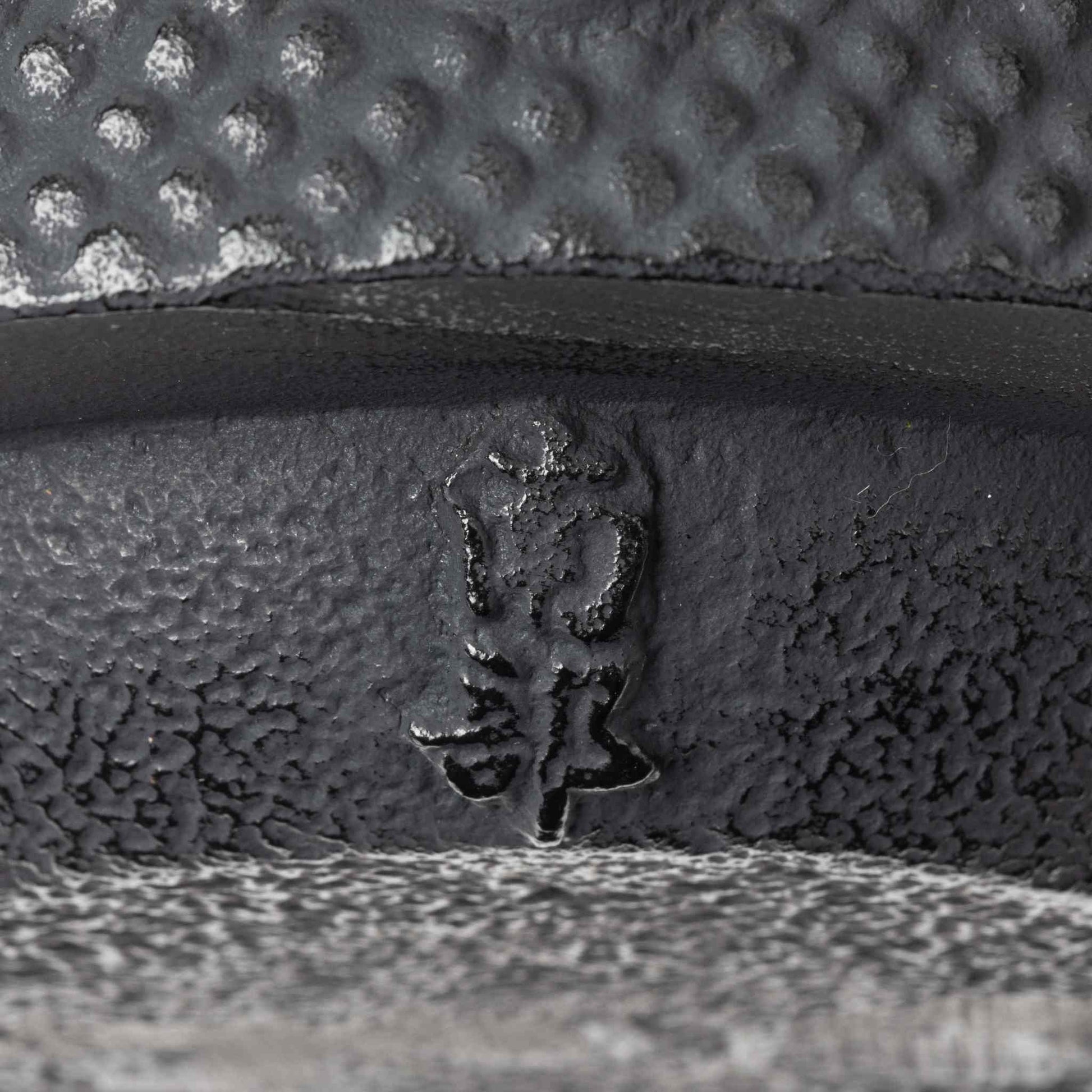 Close-up of the embossed “Nanbu” marking on the base of the black cast iron teapot, indicating its authenticity.