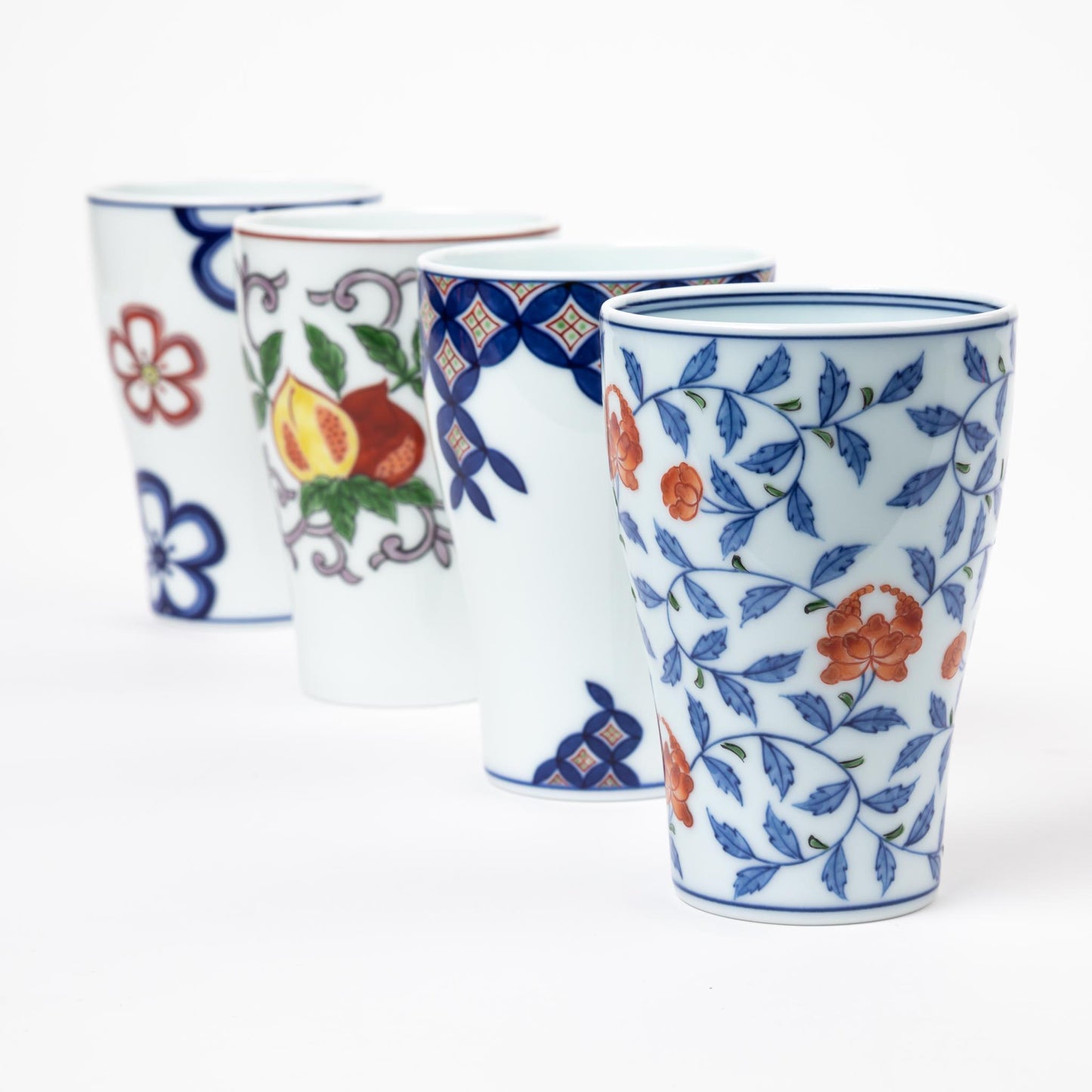 A set of four Gen-emon porcelain cups in various traditional Japanese designs, showcasing hand-painted floral and fruit motifs with intricate geometric patterns, reflecting the diversity of Japanese artistry.