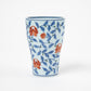 Side profile of a Gen-emon porcelain cup with a detailed floral karakusa pattern, featuring vivid orange flowers and blue vines intricately hand-painted on a white background, showcasing Japanese craftsmanship.