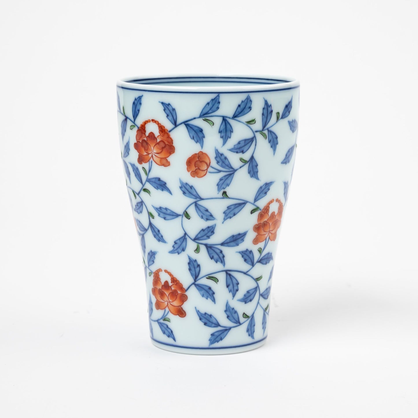 Side profile of a Gen-emon porcelain cup with a detailed floral karakusa pattern, featuring vivid orange flowers and blue vines intricately hand-painted on a white background, showcasing Japanese craftsmanship.