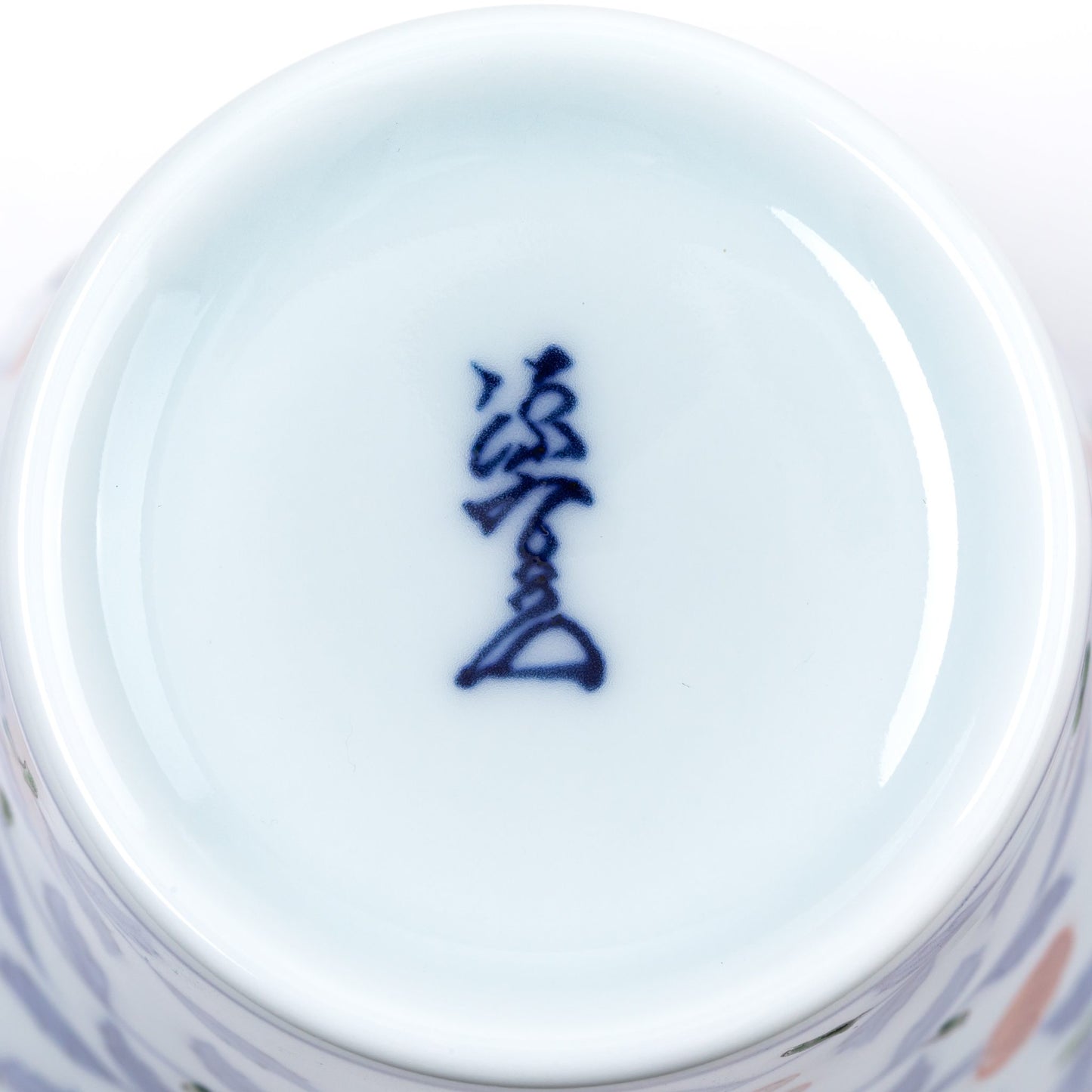 Close-up view of the bottom of a Gen-emon porcelain cup, displaying a blue kanji mark, representing the authenticity and craftsmanship of the Gen-emon kiln.