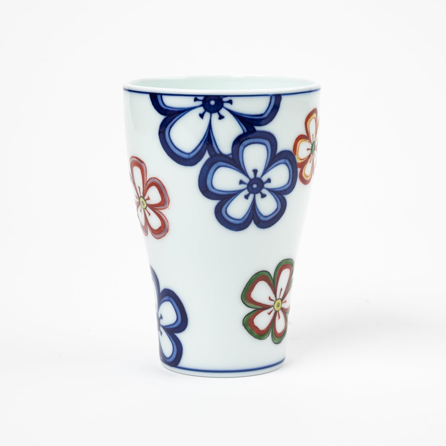 Front view of a Gen-emon porcelain cup, featuring a scattered floral design in blue, red, and green on a white background. The cup’s tapered shape and colorful flower patterns reflect traditional Japanese porcelain craftsmanship.