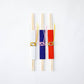 Flat lay of three wooden chopsticks in vibrant dotted sleeves—white, red, and blue—each adorned with elegant Mizuhiki cord decorations, arranged side by side on a clean white background.