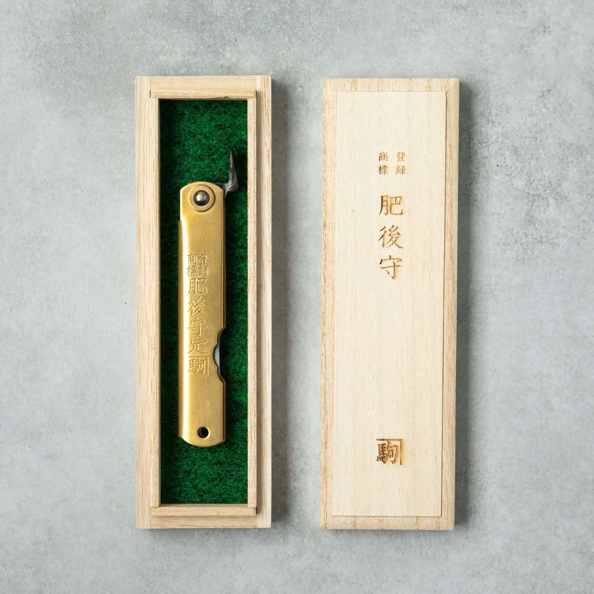 Higonokami Damascus knife presented in a traditional wooden box lined with green felt, with Japanese characters engraved on the box lid, adding elegance to the gift packaging.