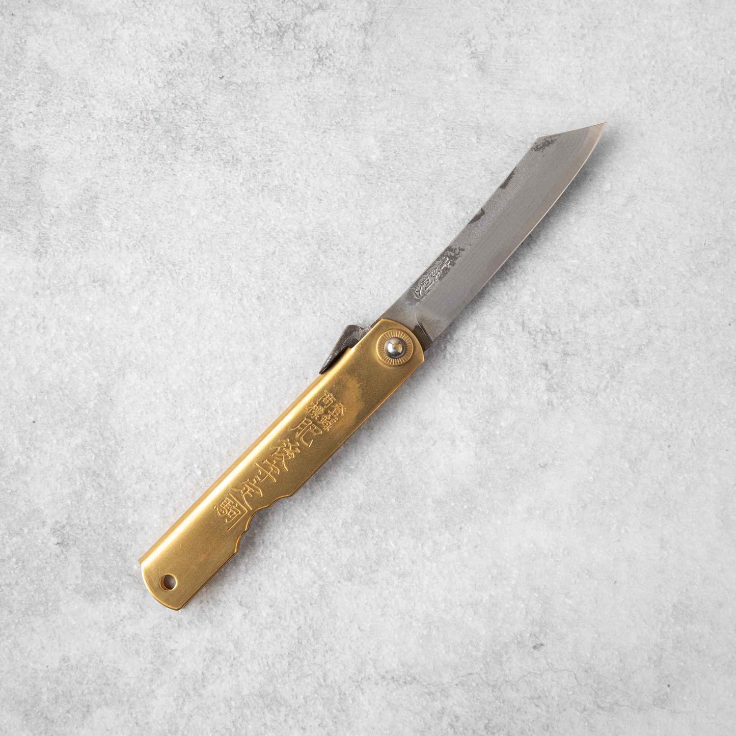 Full view of the Higonokami Damascus knife, featuring a brass handle with engraved Japanese text and a partially extended Damascus blade.