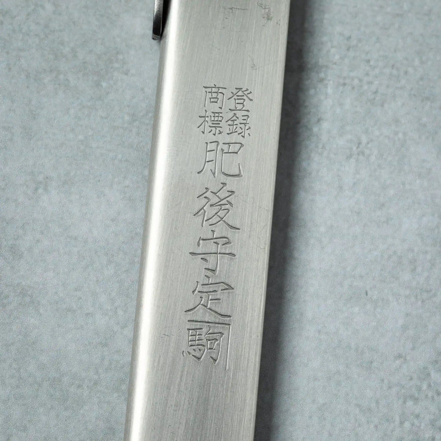 Detailed view of the engraved Japanese characters on the silver handle of a Higonokami VG10 stainless steel knife.