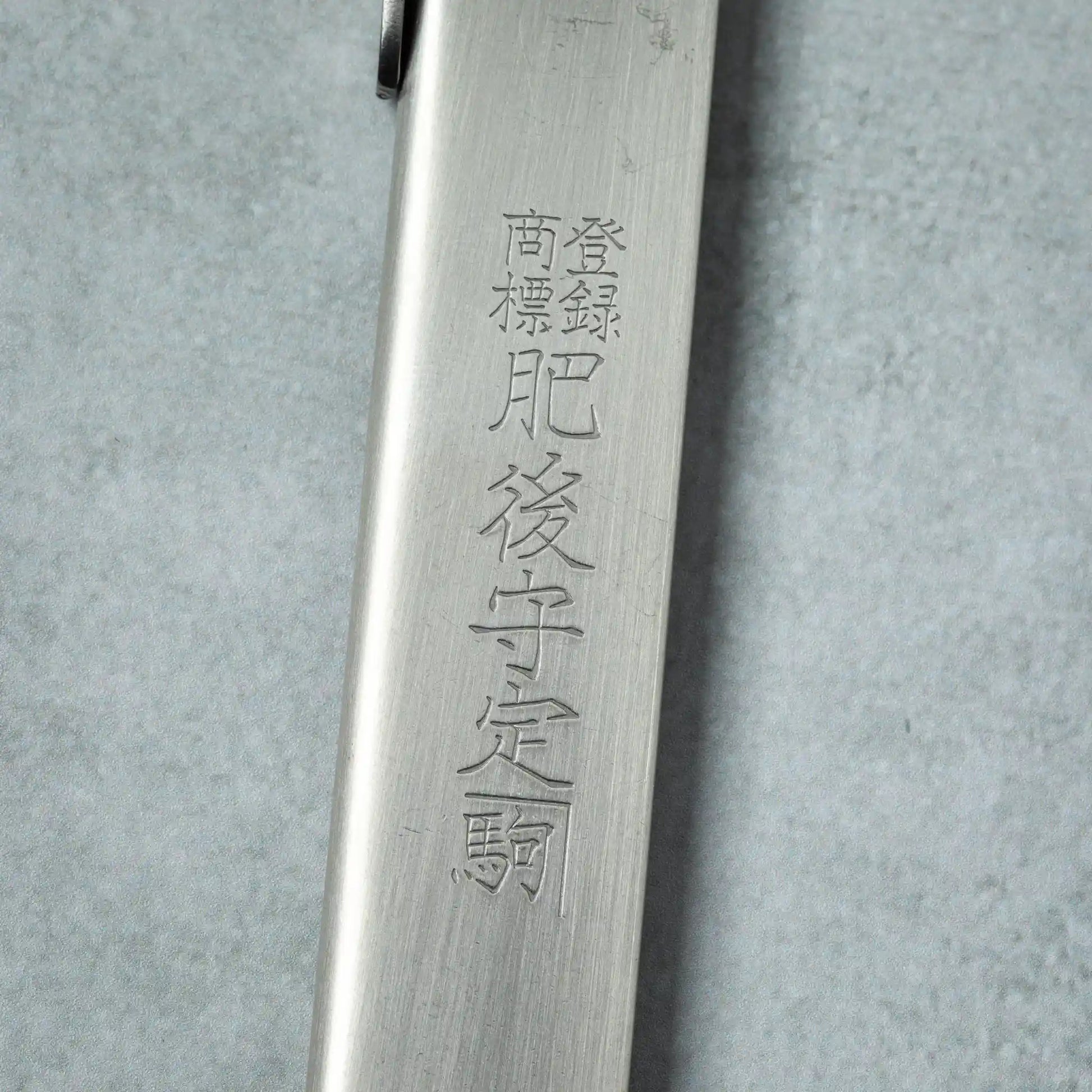 Detailed view of the engraved Japanese characters on the silver handle of a Higonokami VG10 stainless steel knife.