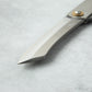 Close-up of the tip of a Higonokami VG10 stainless steel knife blade, showing its sharp, angular design and smooth finish.