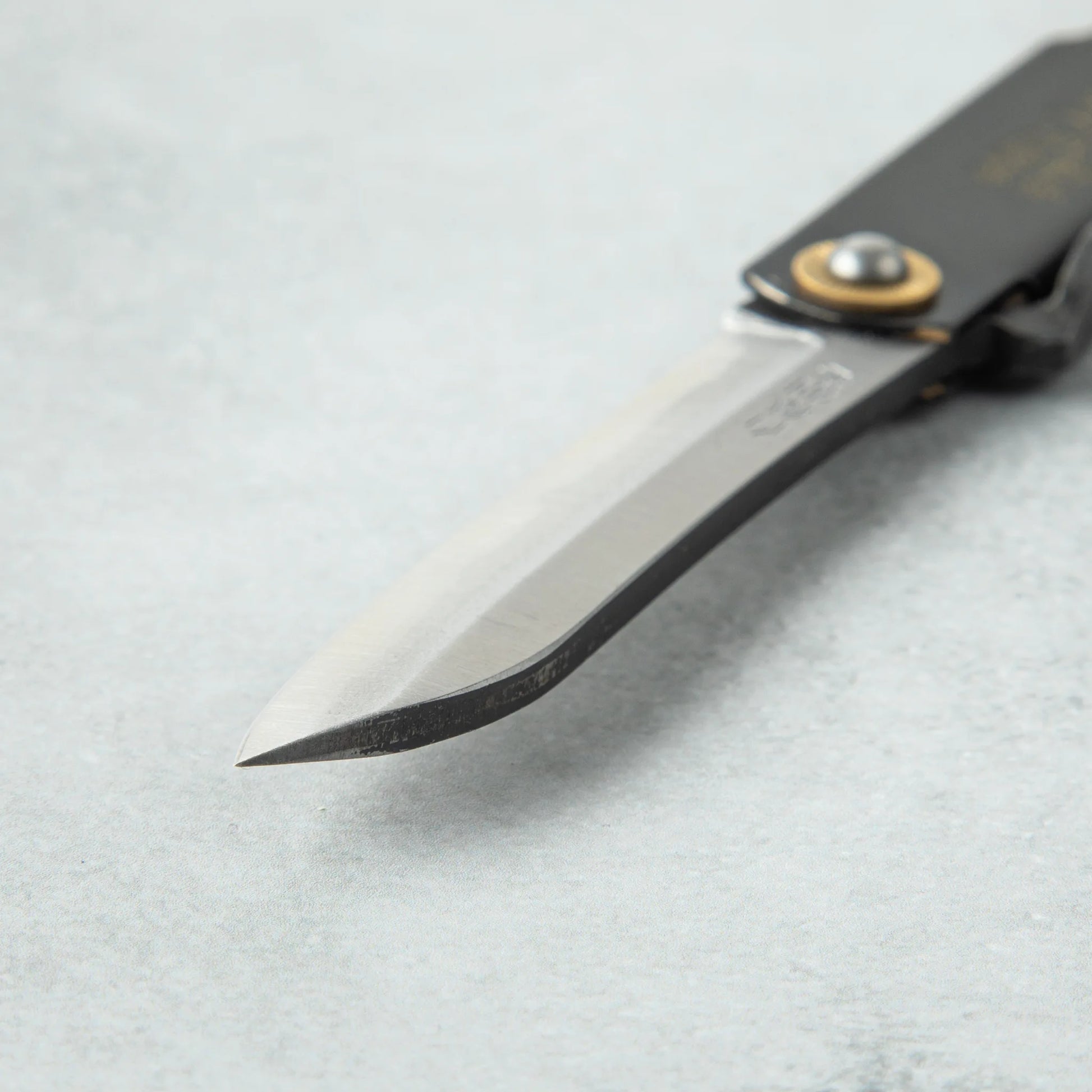 Close-up of the tip of a Higonokami White Steel Bamboo knife, featuring a sleek, sharp blade and a smooth, polished finish.