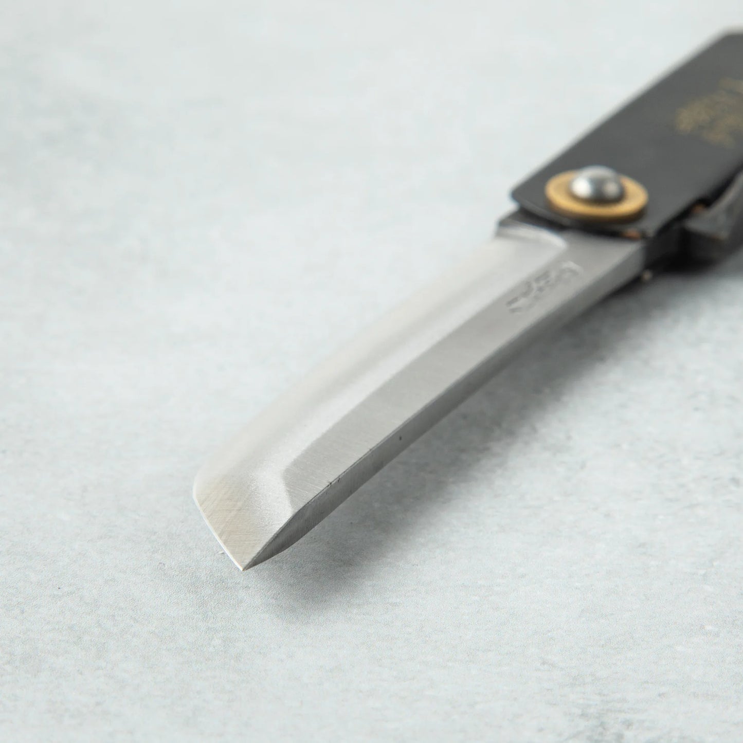 Close-up of the tip of a Higonokami White Steel Sword knife, showcasing its sharp, angled blade with a smooth, polished finish.