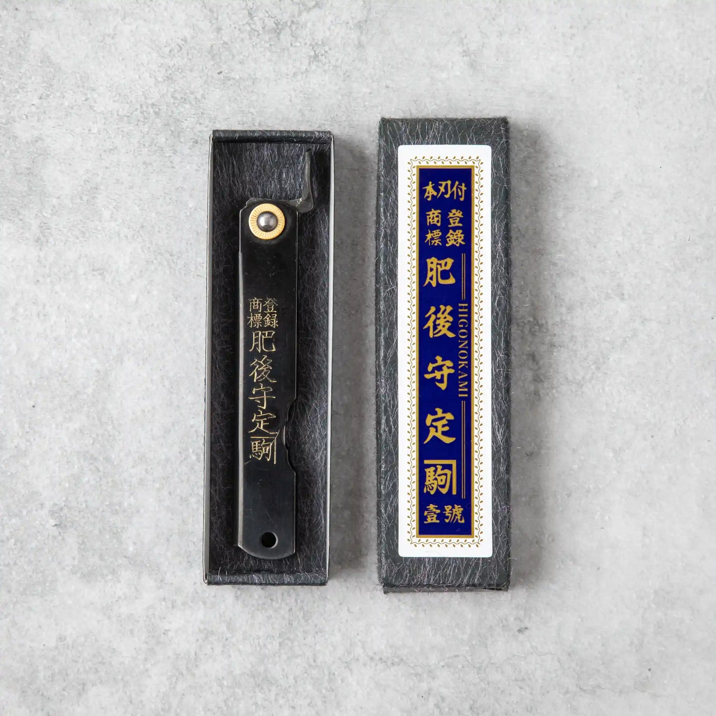 Similar to the first image, this one shows the Higonokami knife in a black box with an identical label in gold and blue, enhancing the classic, traditional appeal. The color difference in the packaging may indicate a variation in model or series.