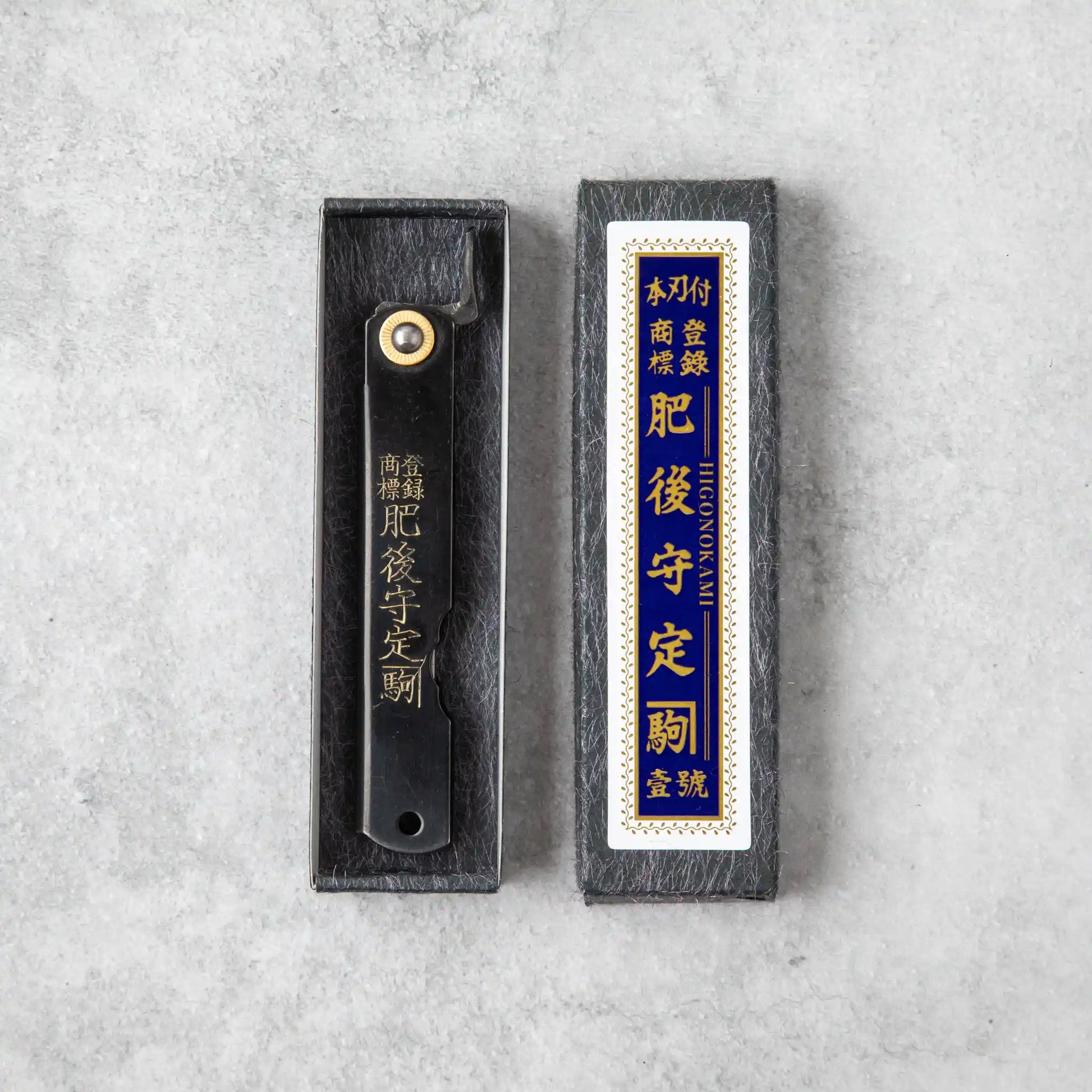 Similar to the first image, this one shows the Higonokami knife in a black box with an identical label in gold and blue, enhancing the classic, traditional appeal. The color difference in the packaging may indicate a variation in model or series.