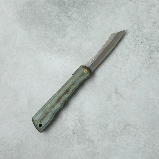 Full view of the Higonokami Woody VG10 knife, with a blue wooden handle and sleek, sharp blade, laid flat on a gray surface.