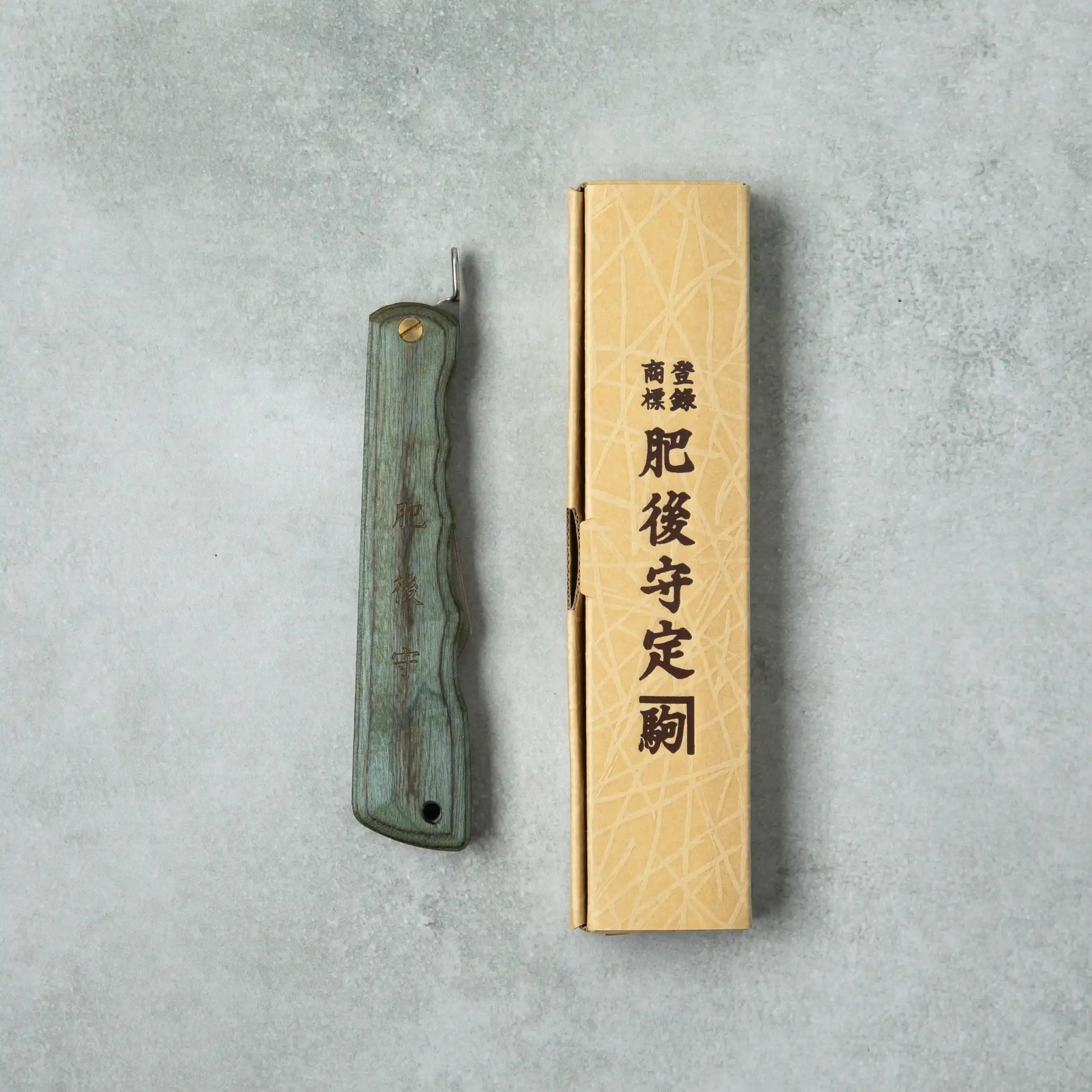 Higonokami Woody VG10 knife with a blue wooden handle, displayed next to its traditional cardboard packaging featuring Japanese characters.