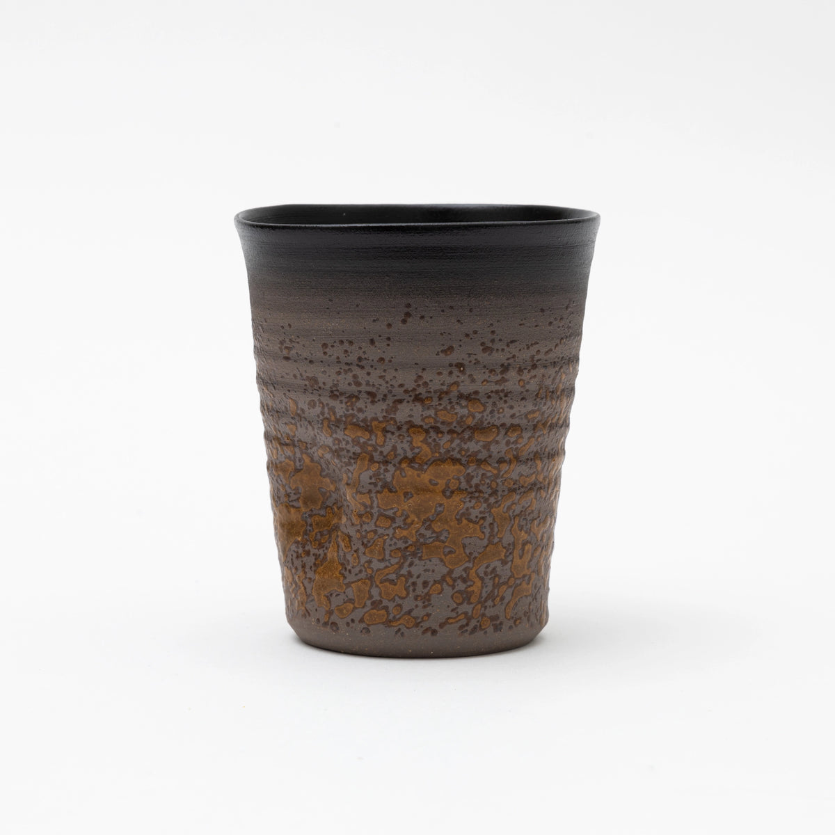 A handleless ceramic tumbler featuring a dark brown ribbed upper section and a heavily textured, speckled ochre glaze on the lower half, set against a white background.
