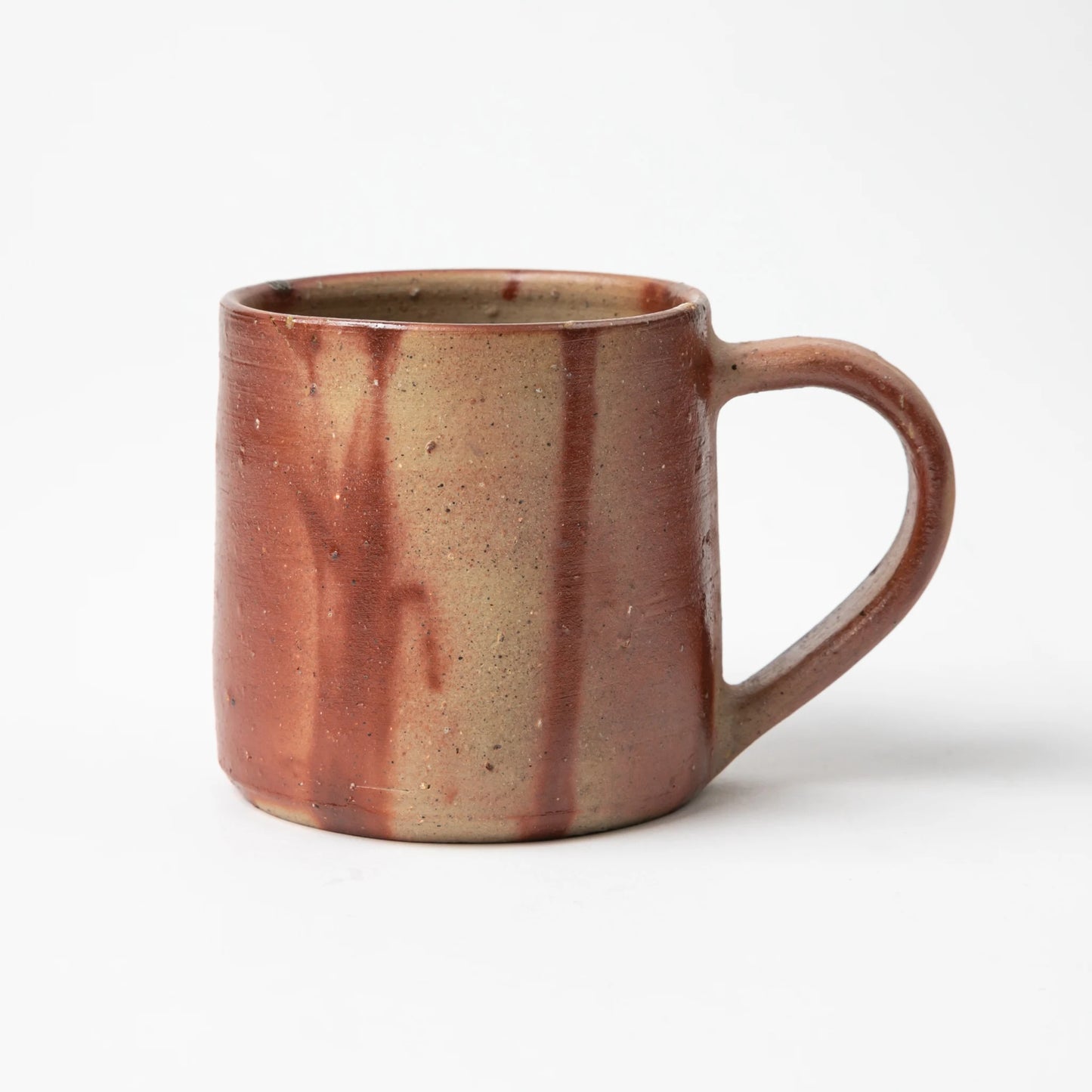 A side view of the Hozan Kiln Hidasuki Mug, displaying a warm earthy gradient of red and beige tones with natural streaks.