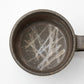 A top-down view of the Hozan Kiln Sangiri Mug, featuring scratch-like patterns etched into its textured dark interior.