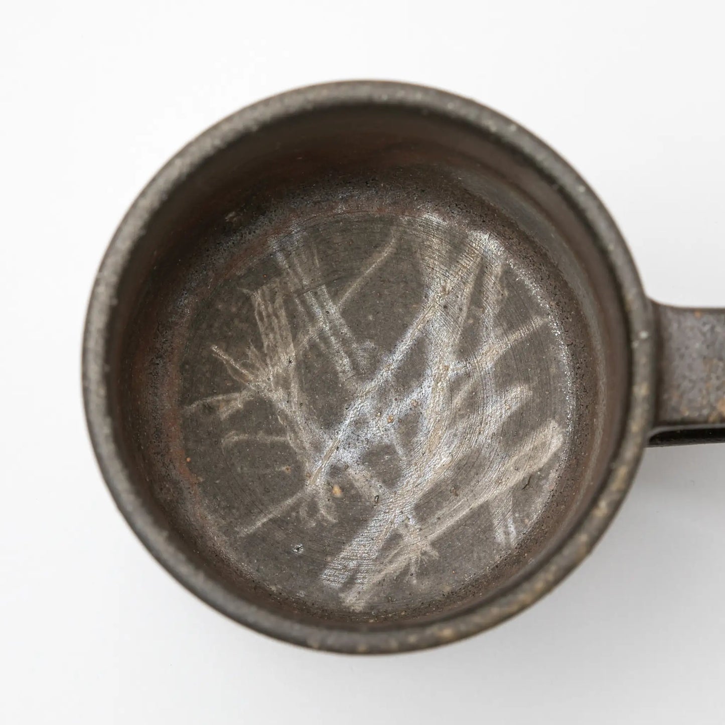 A top-down view of the Hozan Kiln Sangiri Mug, featuring scratch-like patterns etched into its textured dark interior.