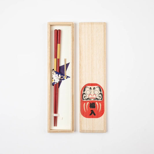 Akadaruma chopsticks set in a natural wooden box featuring a red Daruma illustration on the lid.