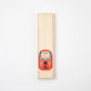 Closed wooden box with a red Daruma illustration, symbolizing good fortune and resilience.