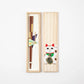 Open paulownia wood gift box featuring gold Ichimatsu lacquer chopsticks with a Maneki-neko illustration on the lid.