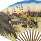 Close-up of the left section of the fan, highlighting finely dressed figures carrying goods near wooden structures and the vibrant Japanese text.