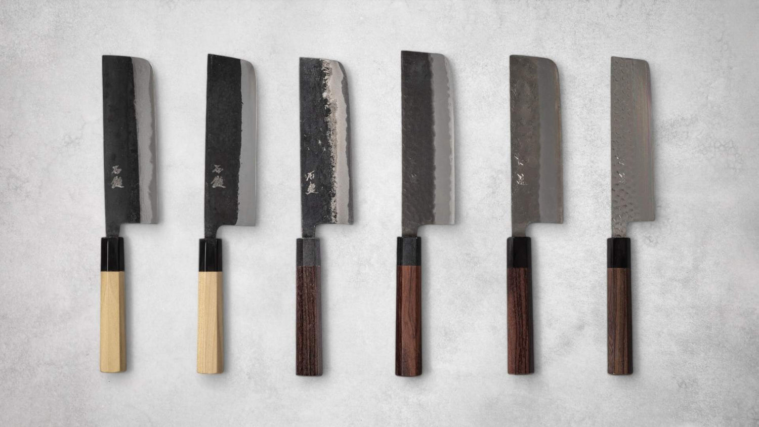 Collection of six Ishizuchi knives with various blade finishes and handle types, displaying a range of traditional Japanese nakiri knives.