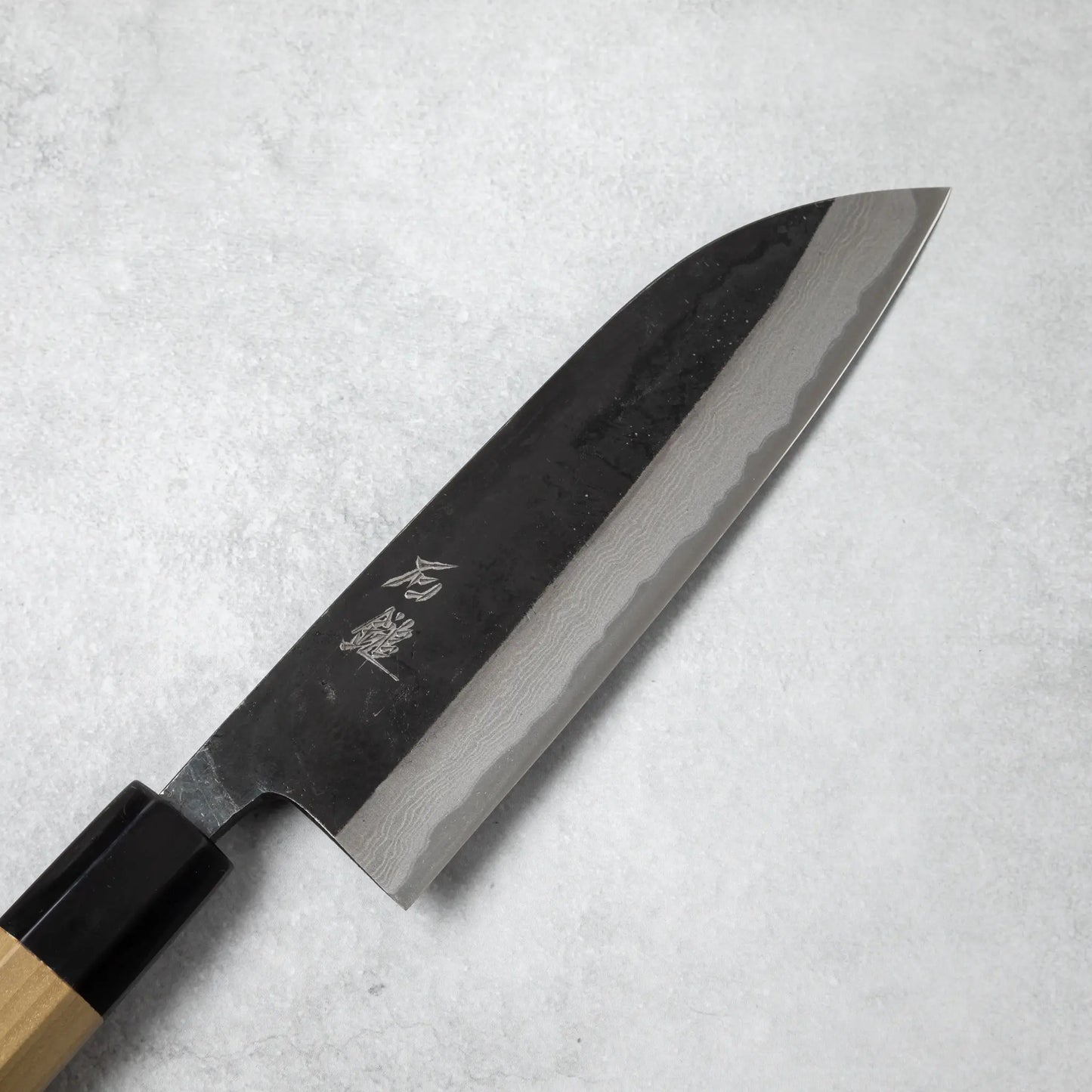 Close-up of the Ishizuchi Blue Steel No.2 Santoku Damascus Knife blade, showing the elegant Damascus wave pattern and engraved kanji.