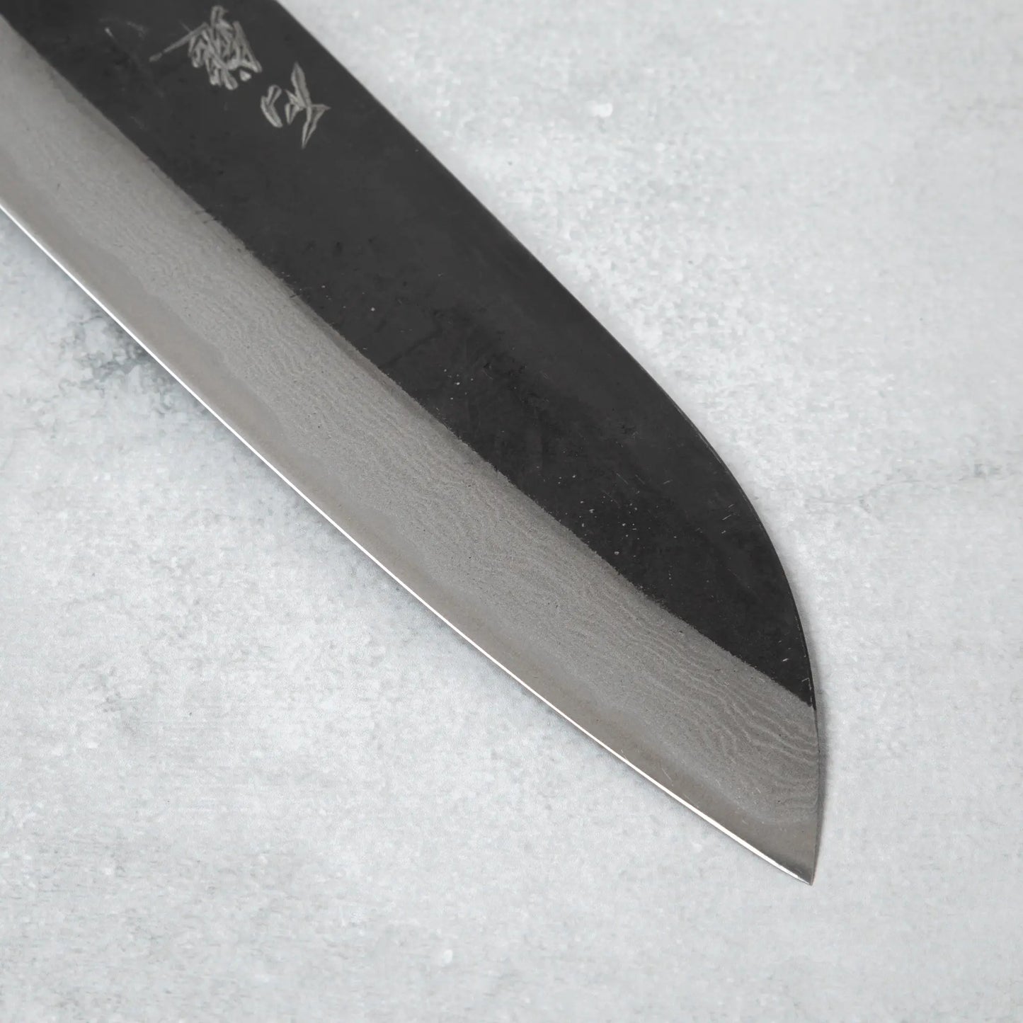 Close-up of the blade edge on the Ishizuchi Blue Steel No.2 Santoku Damascus Knife, highlighting the intricate Damascus pattern and fine craftsmanship.