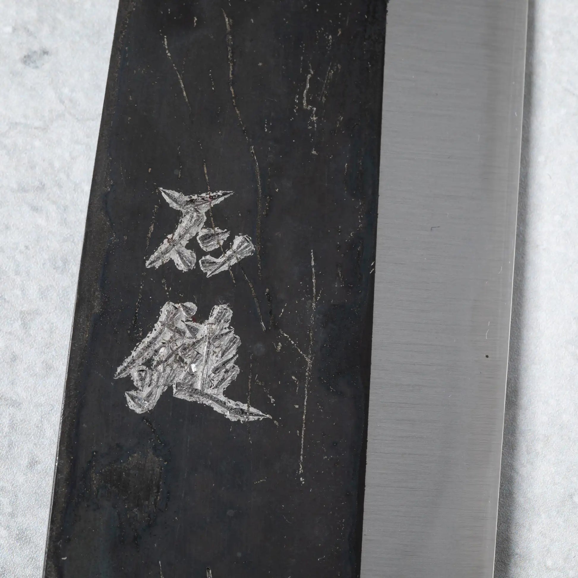 Close-up of the kanji engraving on the Ishizuchi Blue Steel No.2 Chef Knife blade, emphasizing its cultural authenticity.