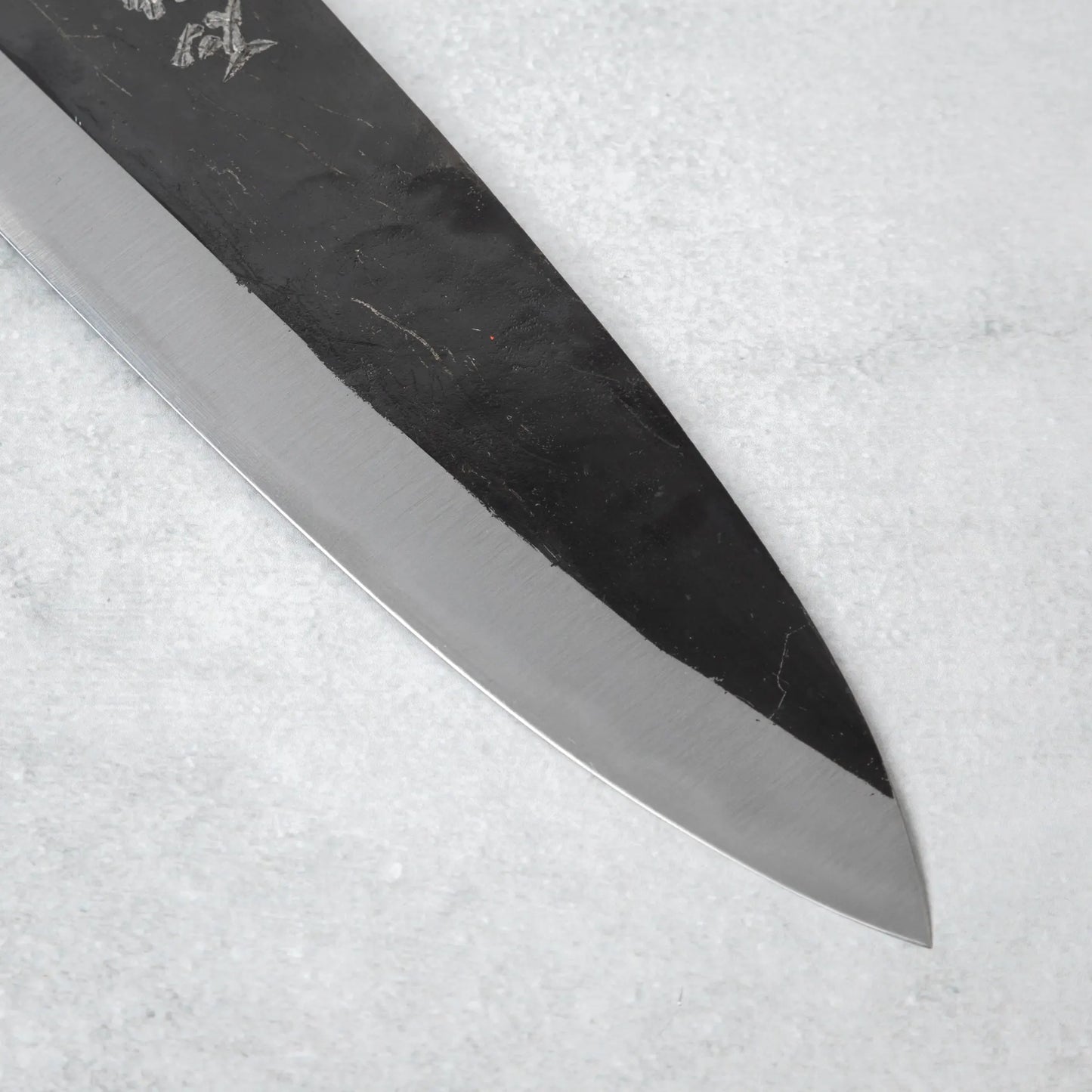 Detailed shot of the blade's edge on the Ishizuchi Blue Steel No.2 Chef Knife, highlighting the sharpness and craftsmanship.