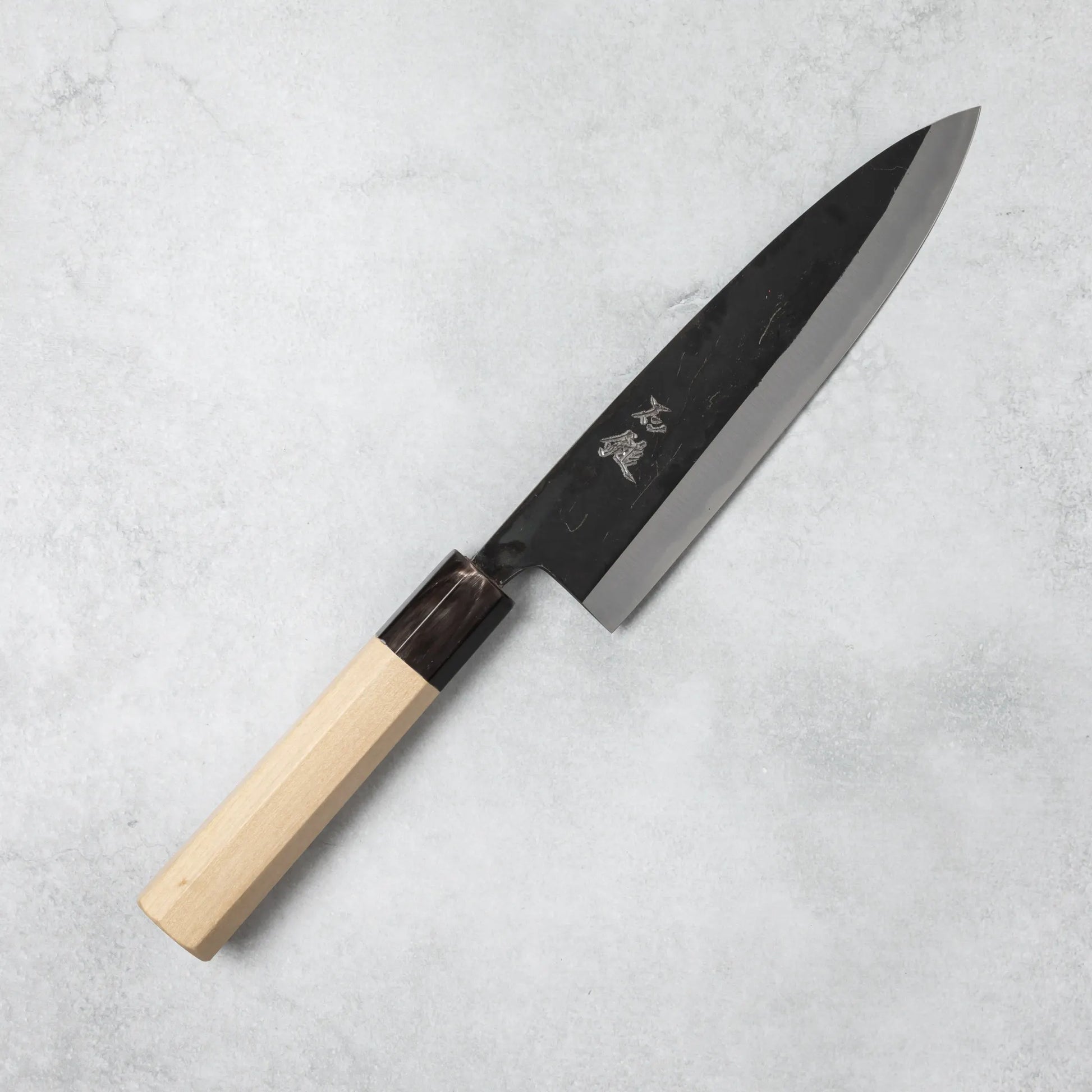 Full view of the Ishizuchi Blue Steel No.2 Chef Knife with a magnolia handle, showcasing its traditional Japanese design on a textured background.