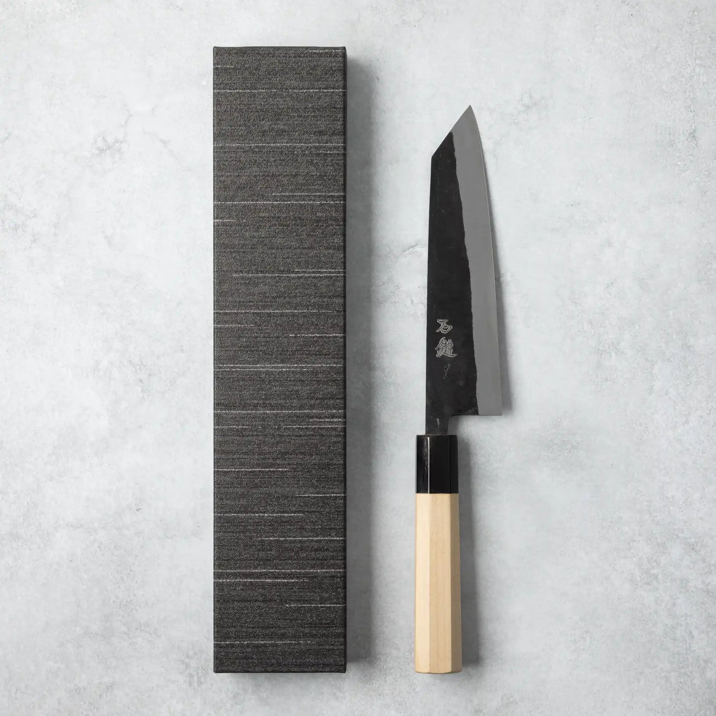 Ishizuchi Blue Steel No.2 Kiritsuke Knife with magnolia handle placed next to a minimalist black box, showcasing a traditional Japanese presentation.