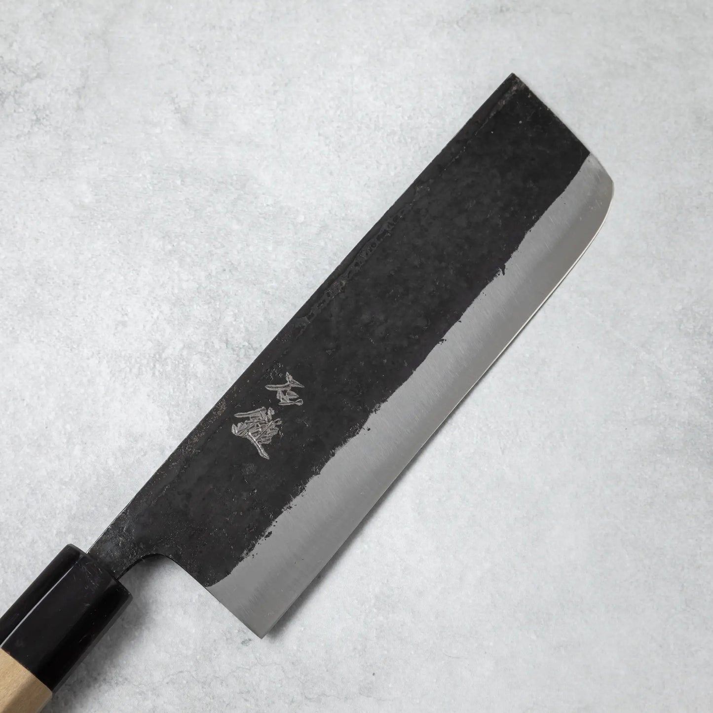 Close-up of the Ishizuchi Blue Steel No.2 Nakiri Knife blade, showcasing its rustic finish and engraved kanji characters.