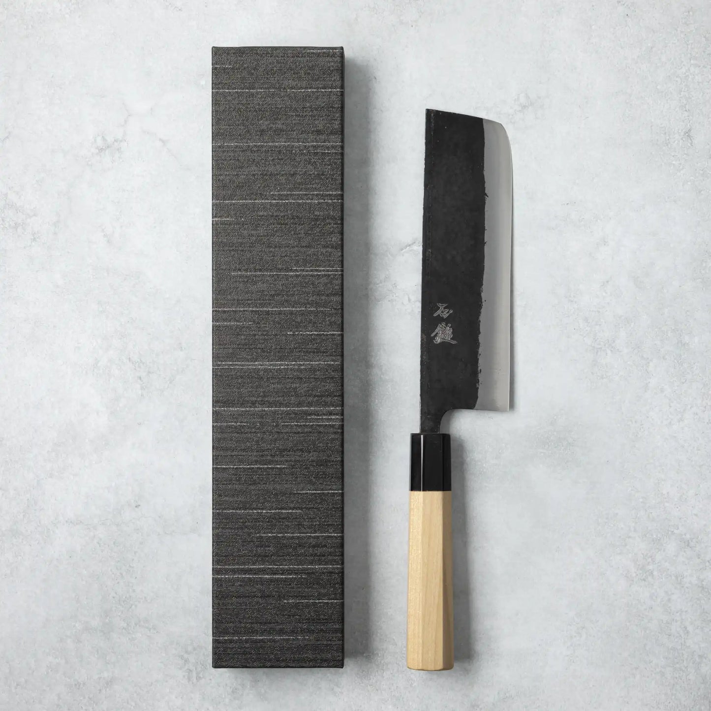 Ishizuchi Blue Steel No.2 Nakiri Knife with magnolia handle displayed next to a minimalist black box, emphasizing traditional Japanese elegance.