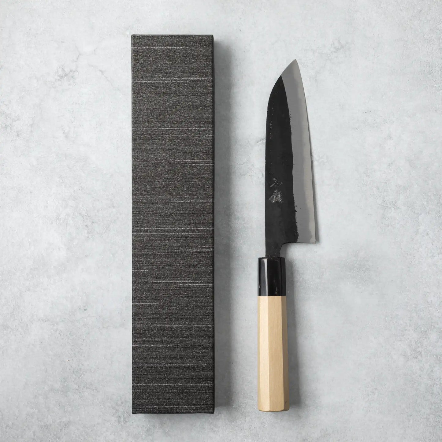 Ishizuchi Blue Steel No.2 Santoku Knife with magnolia handle displayed beside a black box, underscoring its elegant, traditional Japanese presentation.