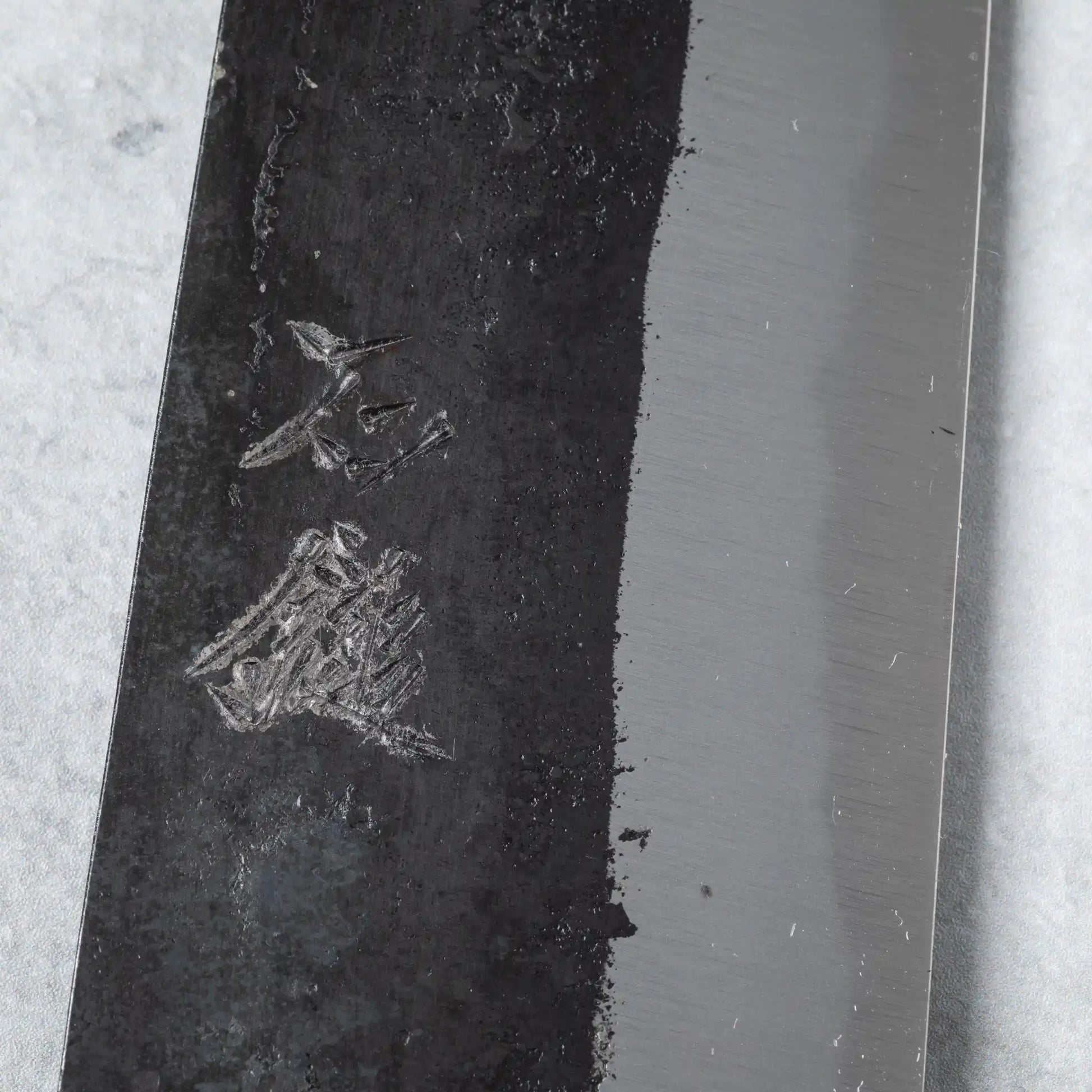 Close-up of kanji engraving on the Ishizuchi Blue Steel No.2 Santoku Knife blade, showcasing its handcrafted Japanese authenticity.