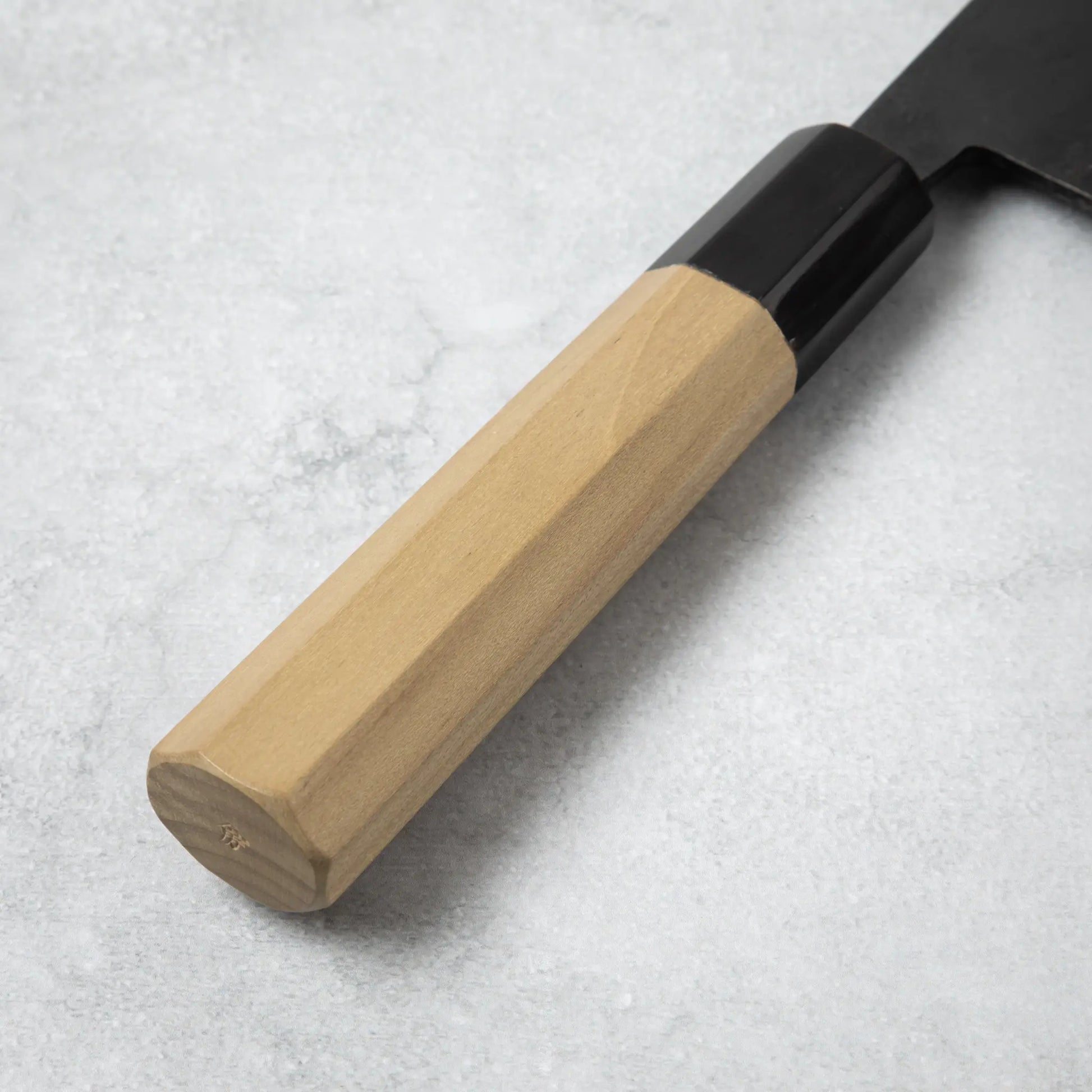 Close-up of the magnolia wood handle of the Ishizuchi Blue Steel No.2 Chef Knife, showcasing its natural wood grain and ergonomic shape.