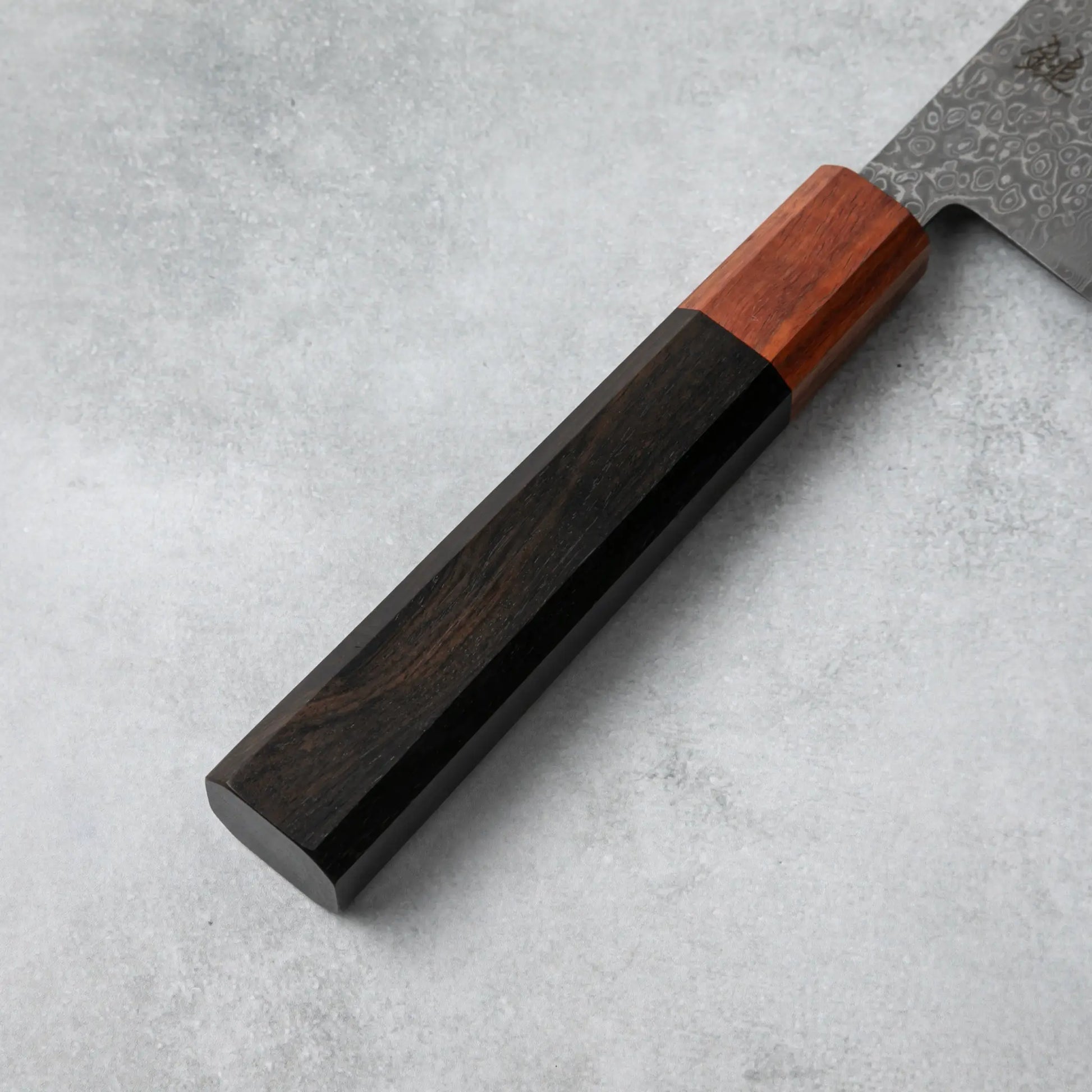 Detailed view of the Ishizuchi VG10 Damascus Chef Knife's ergonomic ebony wood handle, seamlessly joined with a rosewood accent.