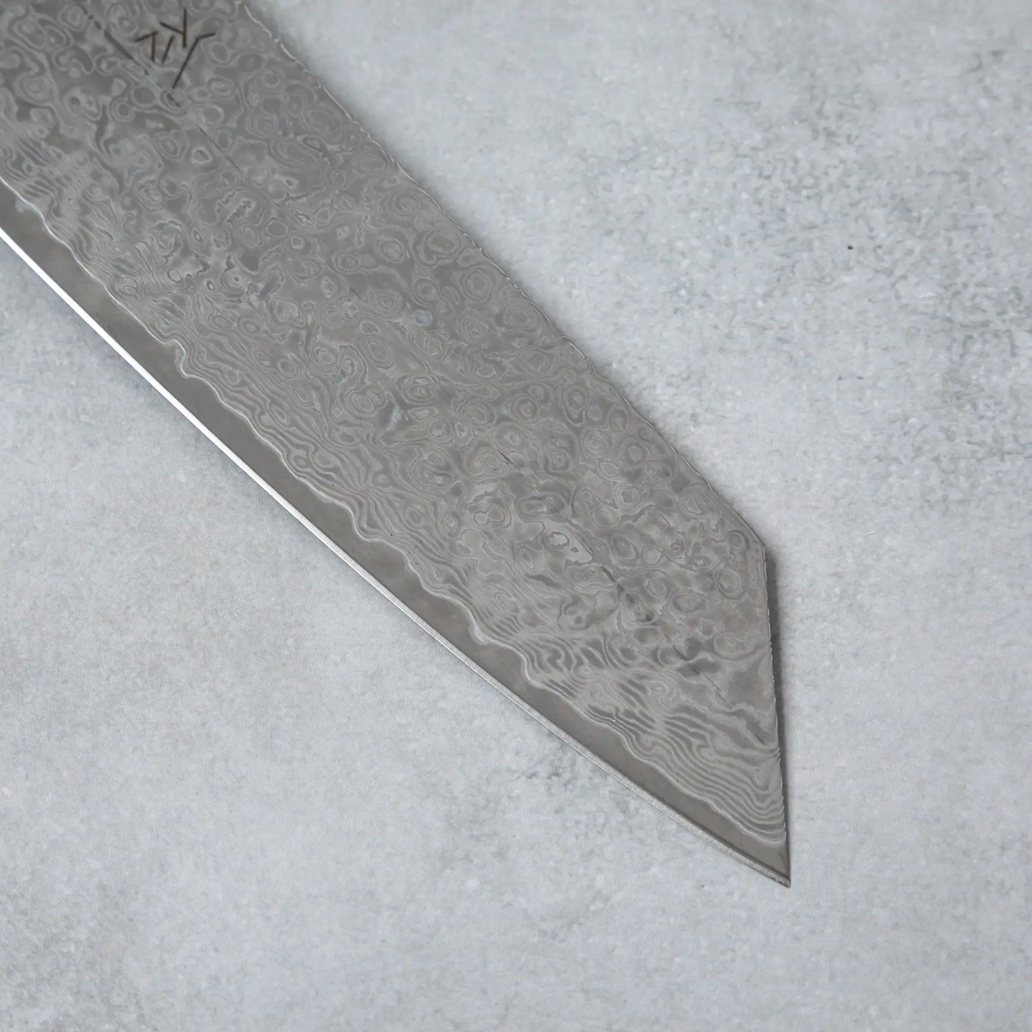 Zoomed-in view of the sharp, angular tip of the Ishizuchi VG10 Damascus Kiritsuke Knife, emphasizing its precise cutting edge and Damascus steel design.