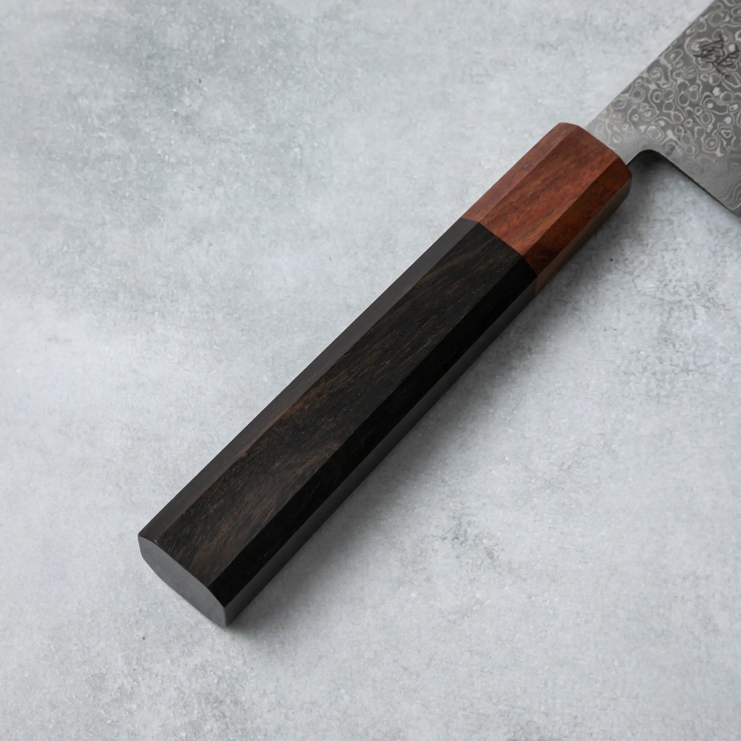 Detailed view of the Ishizuchi VG10 Damascus Kiritsuke Knife's ebony wood handle with a rosewood accent, highlighting its smooth and refined craftsmanship.